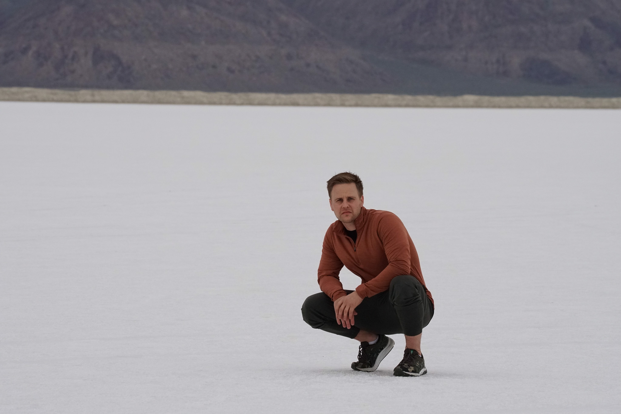 Kellen squatting, snow in the background.